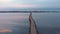 Empty bridge through estuary or lake. Beautiful sunrise at estuary. Wild nature landscape. Calm water surface on lake at sunset