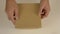 Empty brown carton box. Mans hands close with top gift box. Empty gift box. Soft background. Present gift box. Top view.