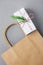 Empty Brown Craft Paper Bag White Christmas Gift Box with Red Ribbon Green Juniper Twig on Gray Background. Sales Discount Shoppin