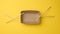 Empty brown paper plate and wooden chopsticks on a yellow background, top view. Disposable tableware