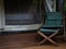 Empty camping wooden chair with green fabric seat and footrest on the terrace.