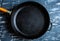 Empty cast iron pan on a dark blue culinary background, top view