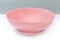 Empty ceramic pink plate on a white surface, side view