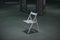 An empty chair in a dark room. A lonely object standing in empty concrete walls at dusk, a symbolism of loneliness of fear,