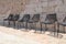 Empty chairs in row under stone wall