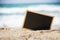 Empty chalkboard on summer tropical sand beach with wood frame for display text. Display design for travel agency concept. Blank