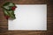 Empty christmas card and holly leafs on old wooden table