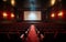 Empty cinema theater with red seats curtains and a blank white screen ready for the audience to enjoy a movie