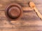 Empty clay bowl with wood spoon on old wooden table. Rural composition, top view. Template for menu, poster or print