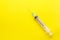 Empty clear syringe with needle on yellow background