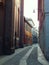 An empty cobbled street in Milan, Italy, lined with a church and old houses, leading with slight twists and turns into distance