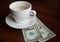 Empty coffee cup and two dollars under saucer