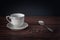 Empty coffee mug on a saucer, coffee beans on dark table boards.