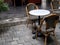 Empty comfortable vintage rattan chair seats with round marble table decorated on grey concrete brick tile floor.