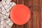 Empty coral circle plate on wooden table with linen napkin