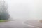 Empty country asphalt road turns in heavy morning fog, blurred effect, illustration of dangers of driving, blurred effect