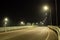 An empty country road with bumpers, lit by street lights. Blurred focus