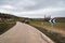 Empty country road through fields on a cloudy spring day