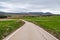 Empty country road through fields on a cloudy spring day