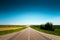 Empty country road on a summer day with green plantings of forest and greenery on the sides