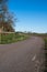 An empty country side road bending through the rural farmland landscape in southern Sweden in springtime