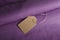 Empty craft paper parice tag on the violet fabric. Fabric store pricing