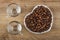 Empty cups, roasted coffee beans in white saucer in heart shape on table. Top view