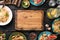 Empty cutting board on dark wooden table with variety food