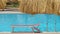 Empty deck chair on swimming pool side in summer resort. Vacations and getaway concept