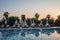 Empty deck chairs and folded parasols arranged at poolside during sunset