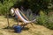 An empty deckchair, a sunhat and watering can and a garden fork