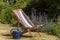 An empty deckchair and watering can in country garden,