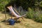 An empty deckchair, watering can and a garden fork