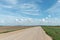 Empty dirt road through the fields. Fluffy clouds on a warm summer Sunny day over a field of wheat. Pure nature away from the big