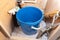Empty dirty plastic trash garbage bin under kiitchen sink with different household goods in a house of a person with