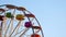 Empty ferris wheel spinning against blue sky.