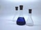 empty and filled laboratory conical flasks with corks on white background