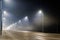 empty foggy night road with rows of lamp posts