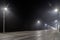 empty foggy night road with rows of lamp posts