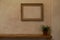 Empty frame with no painting in it hanging on a pale orange wall with Venetian stucco. Art home interior concept with