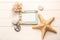 Empty frame with sea shells, starfishes and stones on white wooden background