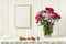 Empty frame on the wall, bouquet of Turkish carnations and garden strawberries