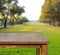 Empty free space top wood table on green grass field against sun