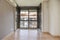 An empty front windowed living room with a long aluminum radiator below