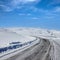 Empty frozen asphalt road and snow covered landscape with mountain over blue sky in winter time