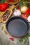 Empty frying pan, vegetables and spices on wood background