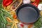 Empty frying pan, vegetables and spices on wooden background