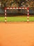 Empty gate. Outdoor football or handball playground, light red crushed bricks surface on ground