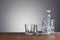 Empty glass carafe, prepared for the alcohol drink on grey background and wood