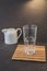 Empty glass and white cream/empty glass on a wooden stand and white cream on a dark table